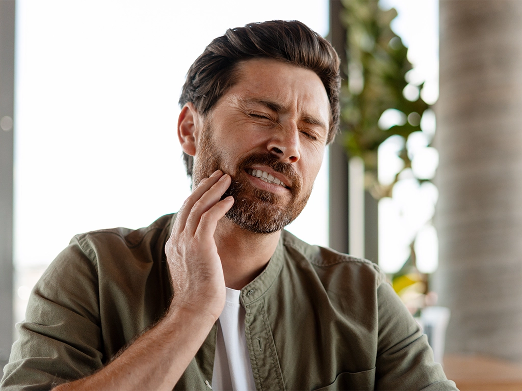 Man suffering from strong toothache touching his cheek